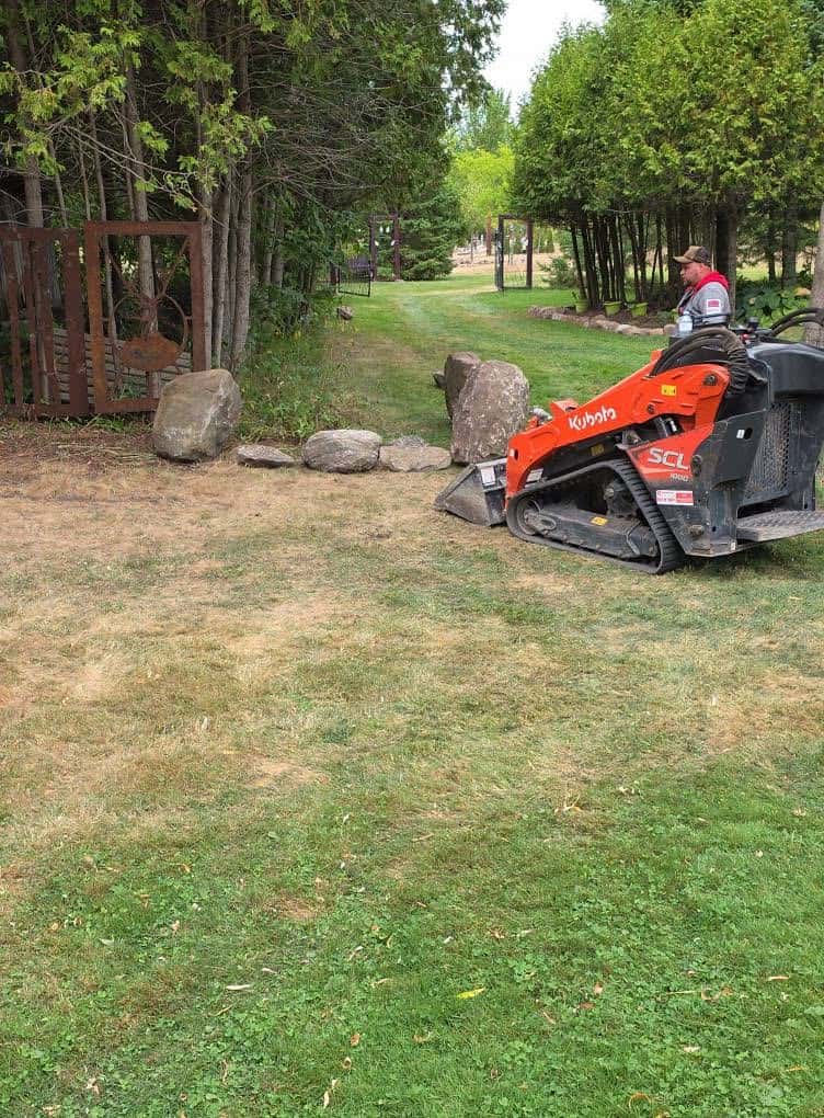Home Pride Landscaping operator placing boulders with a Kubota compact track loader