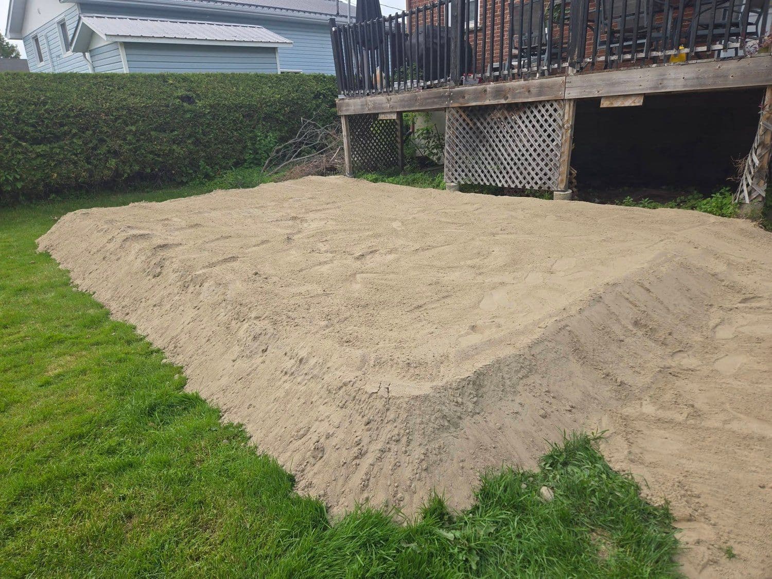 Large graded topsoil pad built up beside a backyard deck
