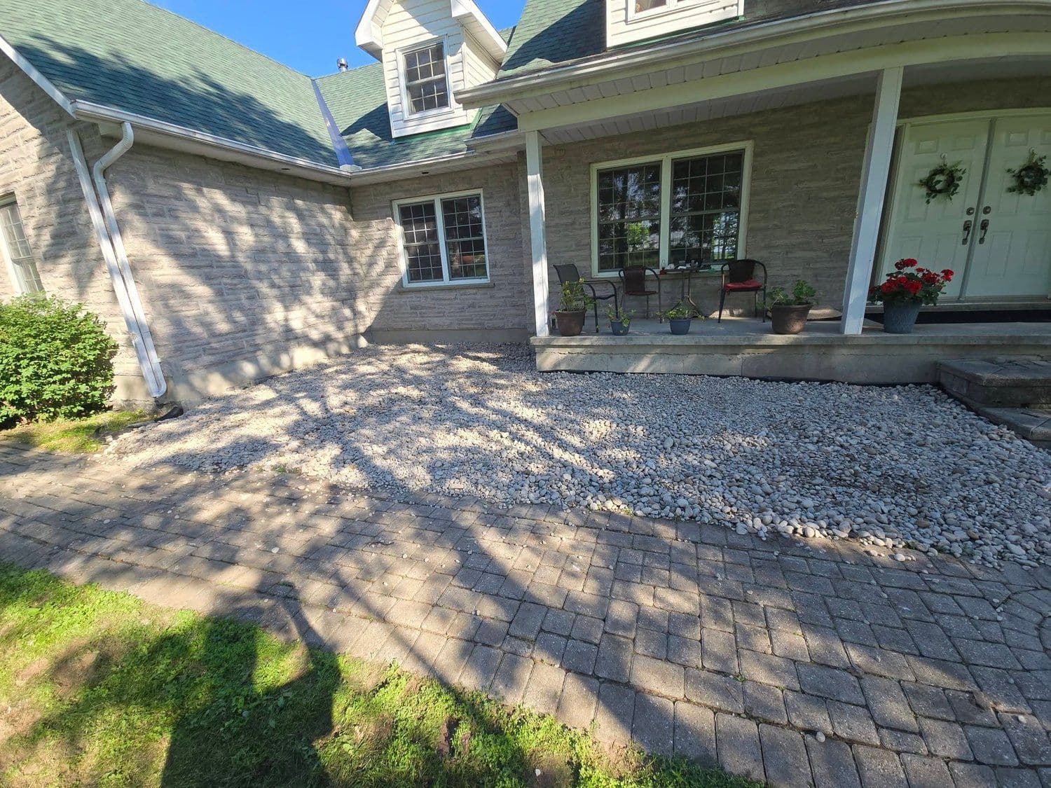 Stone farmhouse porch with new river-rock beds and interlock walkway