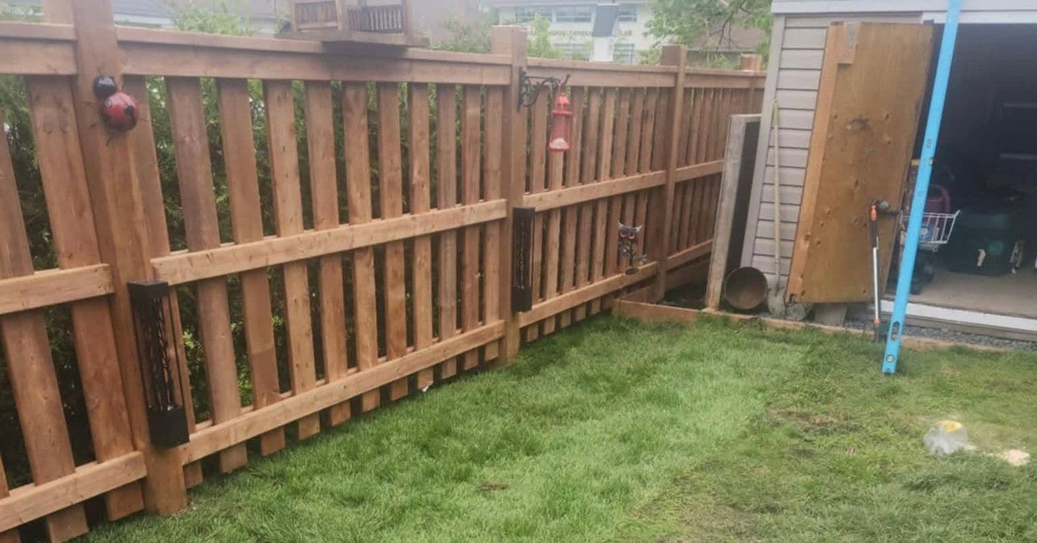 Fresh sod installed along a new wood privacy fence in a backyard
